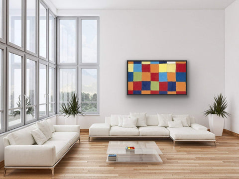 Framed poster with bold geometric design and vibrant colors in a modern living room setting.