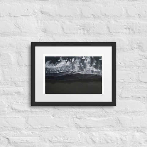 Framed poster with abstract black and white design on brick wall.
