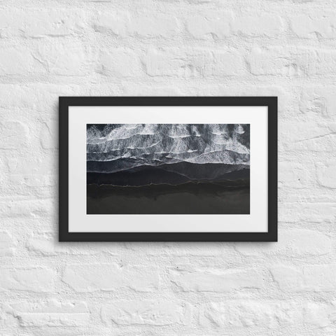 Framed poster with abstract black and white design on textured wall.