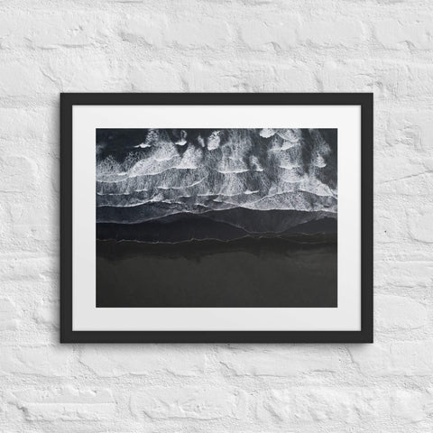 Framed poster featuring a minimalist ocean wave design mounted on a brick wall.