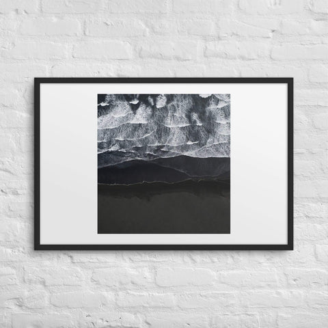 Framed poster with abstract ocean wave design on a white brick wall.