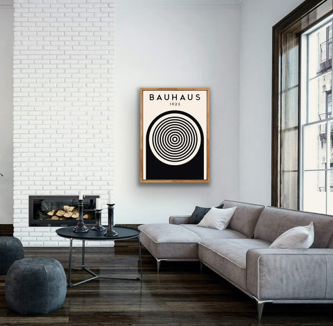 Modern matte paper poster with bold geometric Bauhaus design in black and white, framed in wood, displayed in a stylish living room.