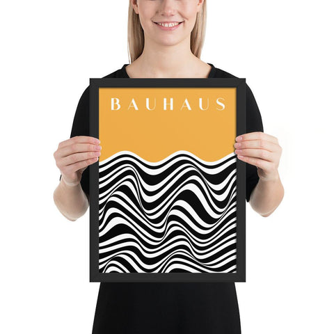 Person holding a framed Bauhaus poster with abstract black and white wave pattern and yellow background.